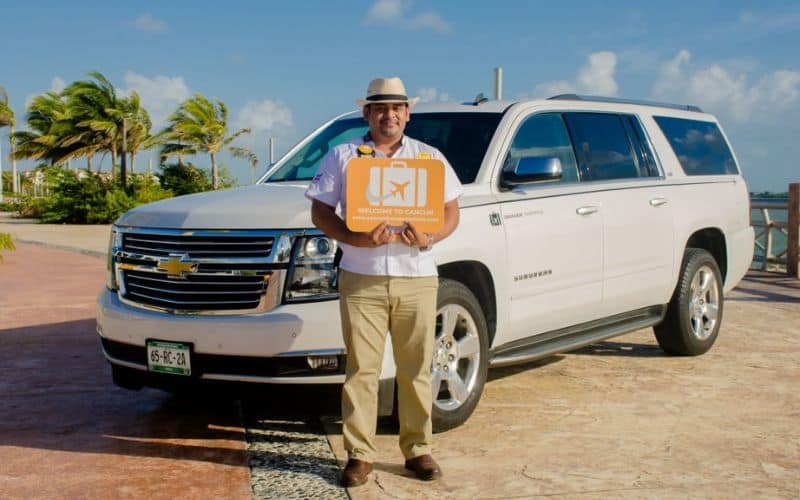 man holding sign in front of white SUV from the best cancun to tulum shuttle service