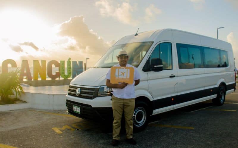 man holding sign in front of white van from the best cancun to tulum shuttle service