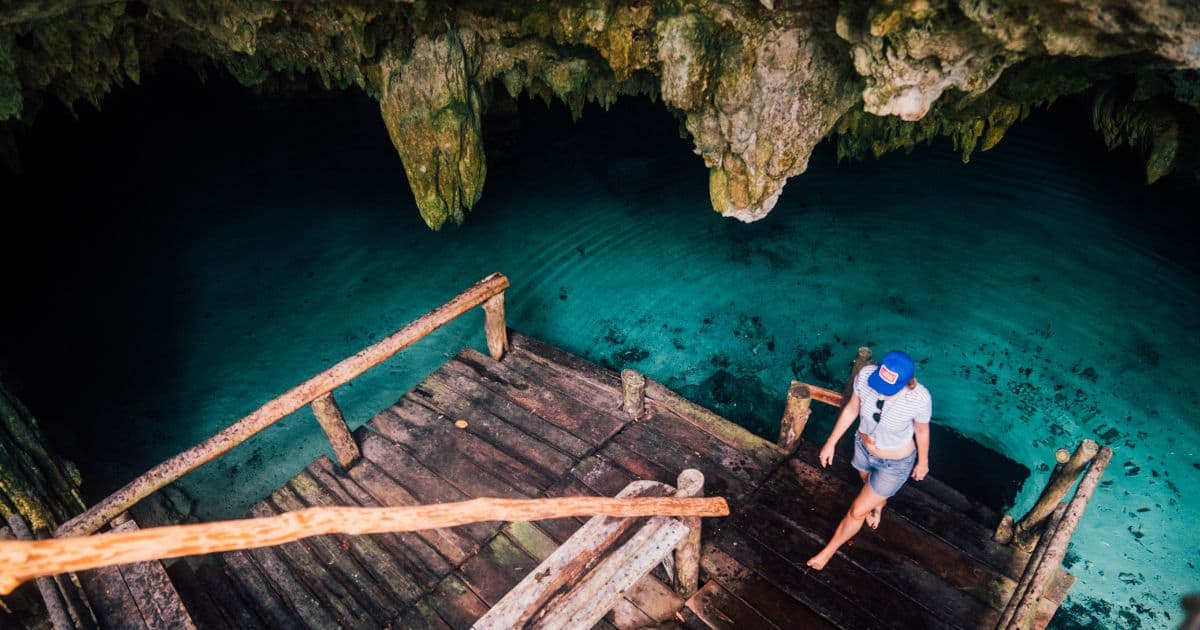 woman standing on the wooden platform of a cave cenote in Mexico | what to bring to cenotes